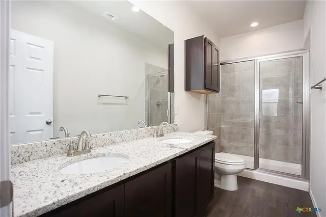 an empty room with wooden floor chandelier fan and windows