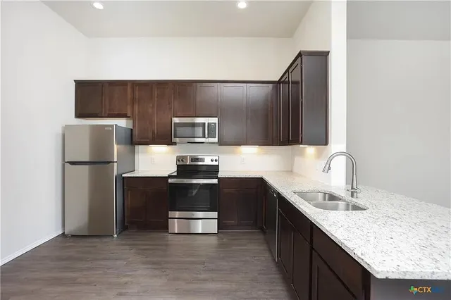 a kitchen with kitchen island granite countertop stainless steel appliances and wooden cabinets