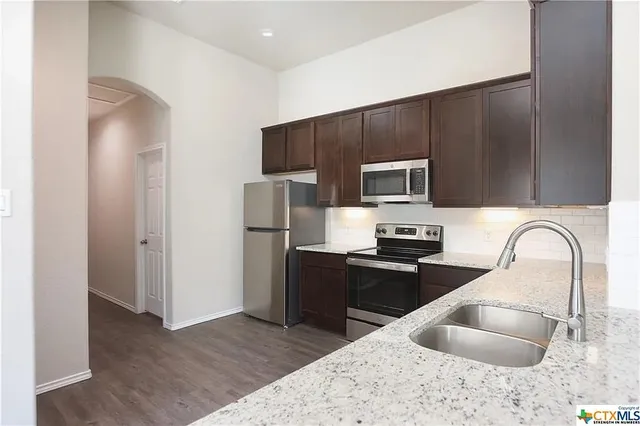 a kitchen with stainless steel appliances granite countertop a refrigerator and a sink