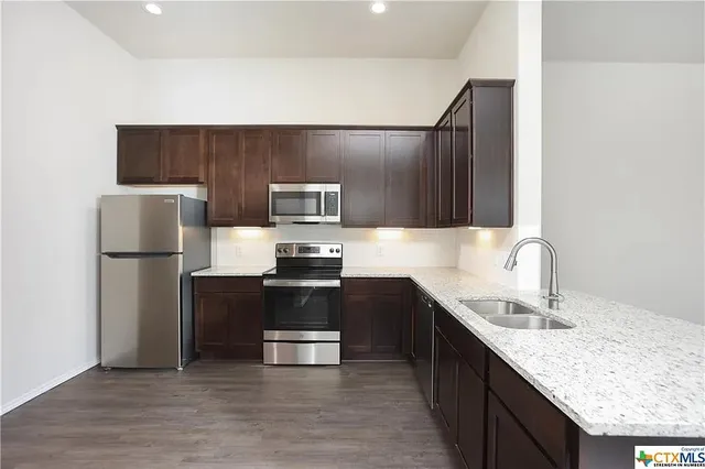 a kitchen with kitchen island granite countertop stainless steel appliances and wooden cabinets