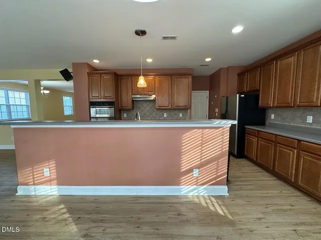 a kitchen with stainless steel appliances granite countertop a stove a sink dishwasher and a refrigerator with wooden floor