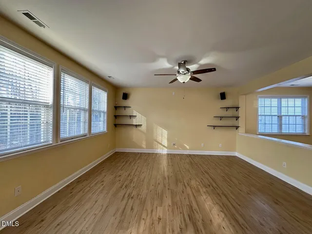 a view of an empty room with a window and wooden floor