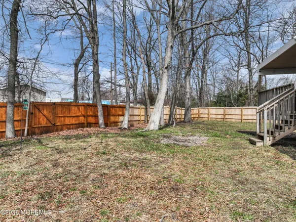 a view of backyard with wooden fence and trees