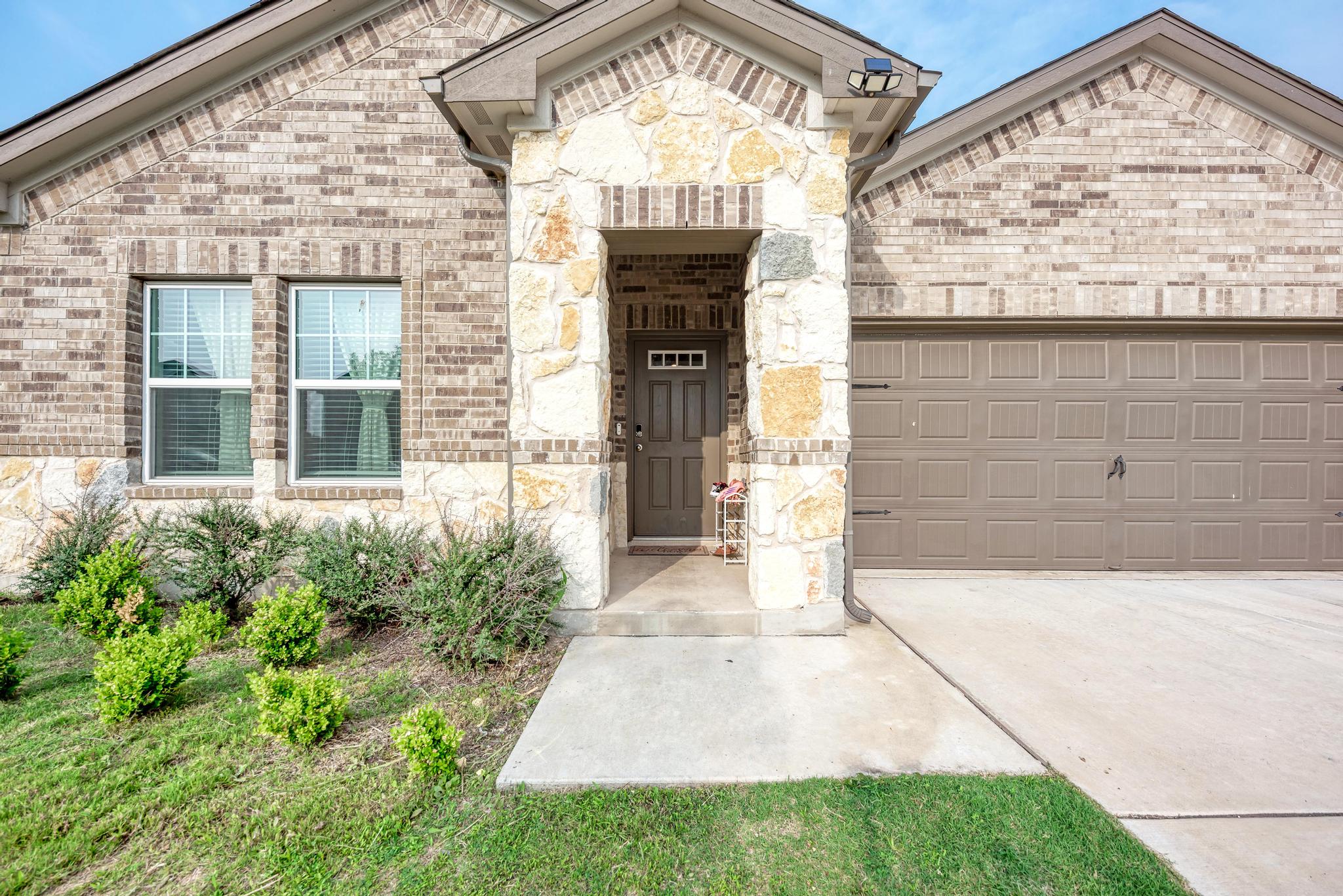 305 Windy Reed Road Hutto, TX 78634 - Photo 3 of 35 A stone-accented entryway highlights this brick exterior complete with a two-car garage.
