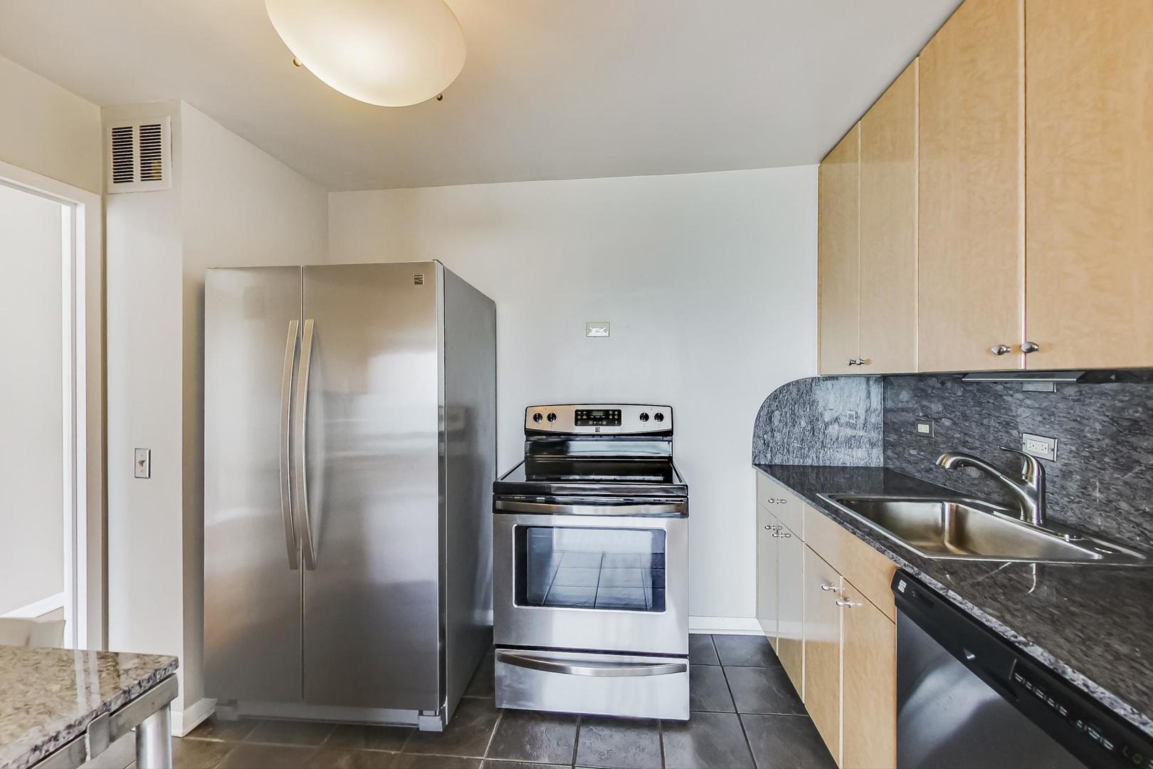 5445 North Sheridan Road, Unit 1706 Chicago, IL 60640 - Photo 8 of 26 a kitchen with granite countertop a refrigerator and a stove top oven