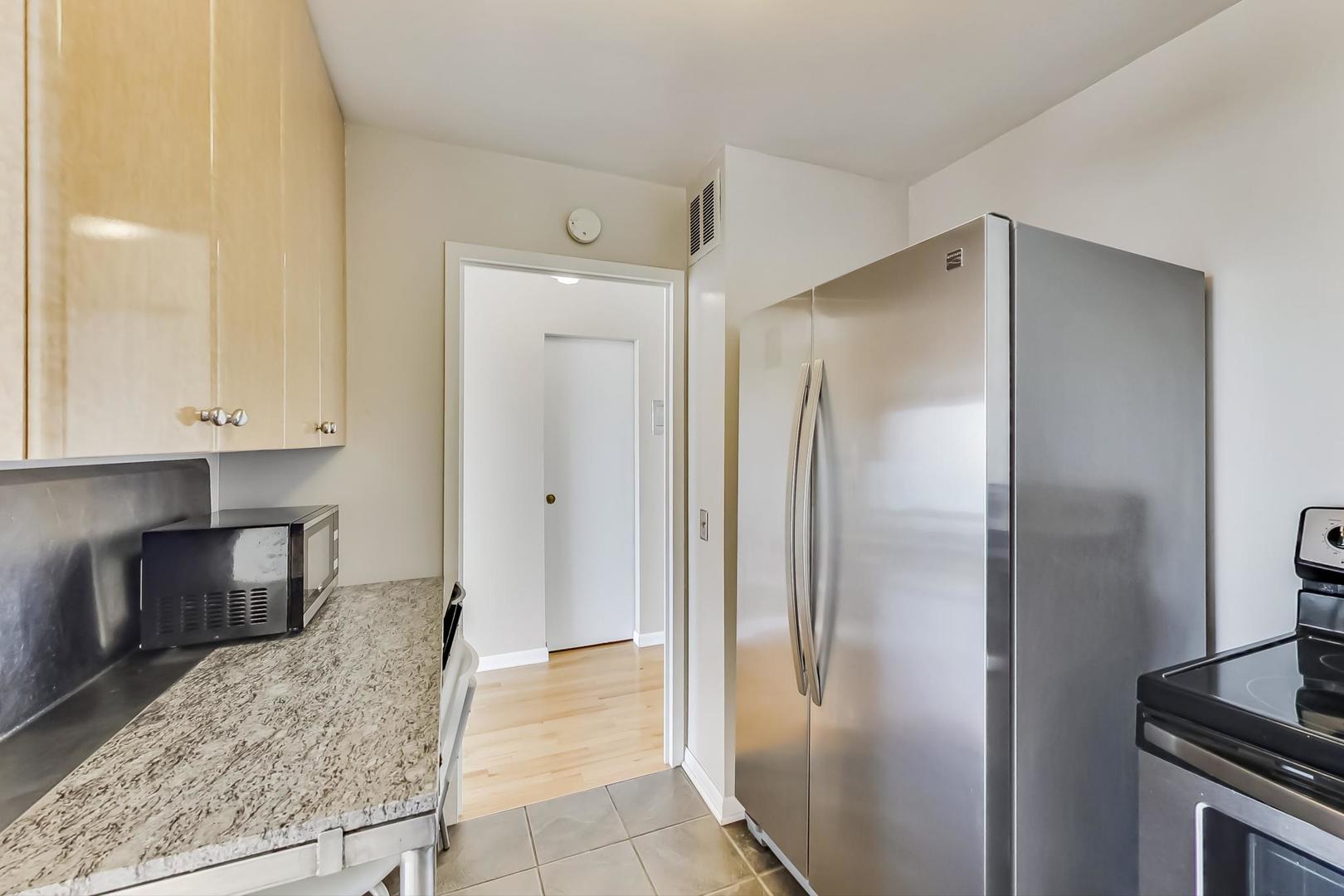 5445 North Sheridan Road, Unit 1706 Chicago, IL 60640 - Photo 9 of 26 a view of a refrigerator in kitchen and an empty room