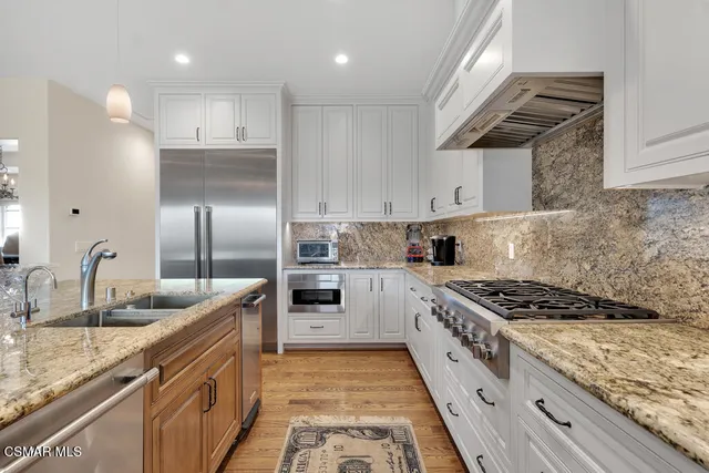 a kitchen with kitchen island granite countertop a sink cabinets and stainless steel appliances