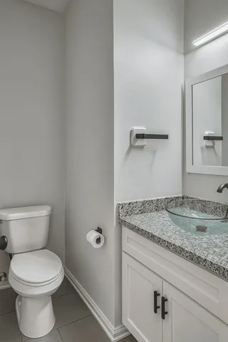 a bathroom with a granite countertop toilet and a sink