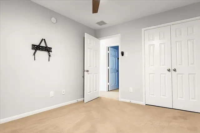 an empty room with closet and a chandelier fan