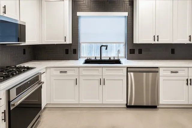 a kitchen with white cabinets and appliances