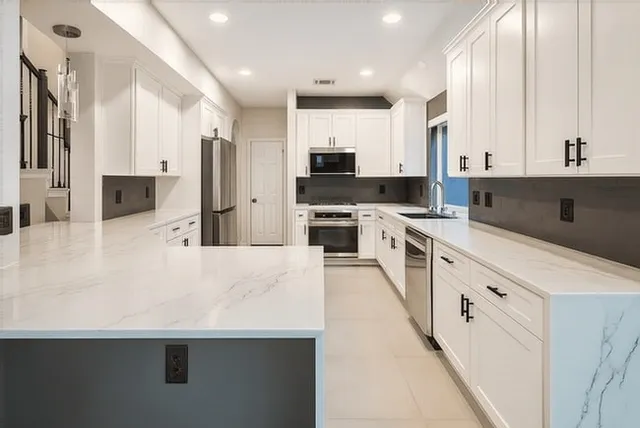 a large white kitchen with stainless steel appliances