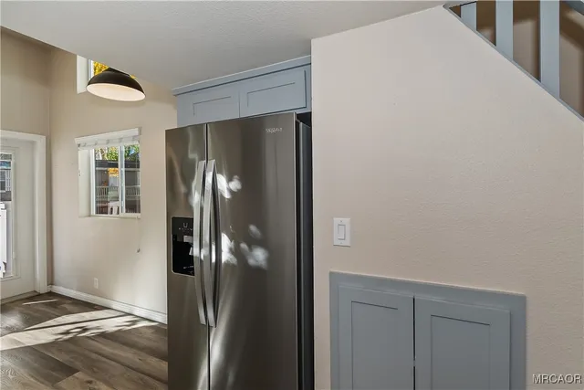 a view of a livingroom with wooden floor and a refrigerator