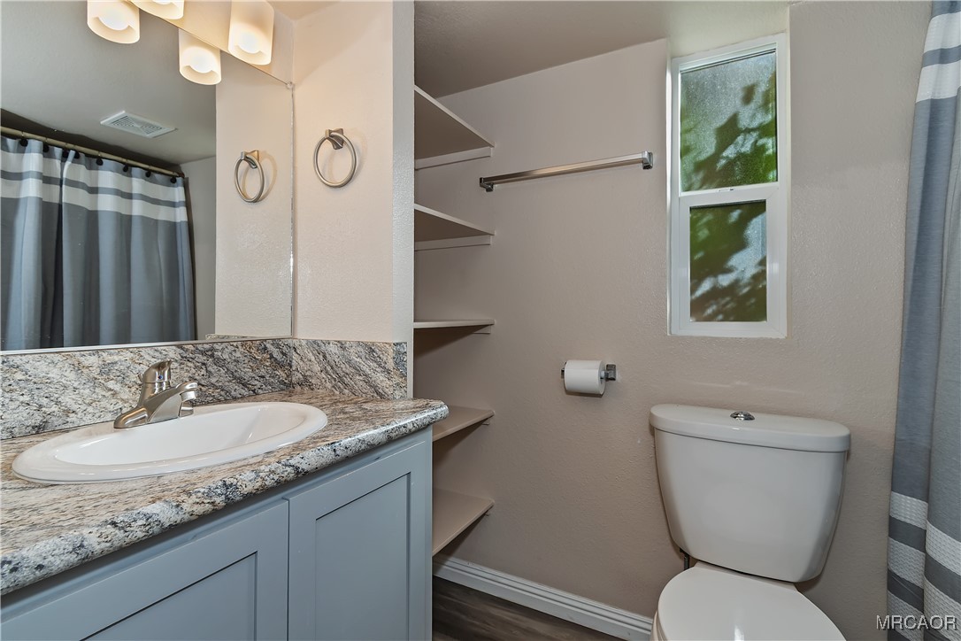 547 Alden Road, Unit RV5 Big Bear Lake, CA 92315 - Photo 16 of 34 a bathroom with a granite countertop toilet a sink and a mirror