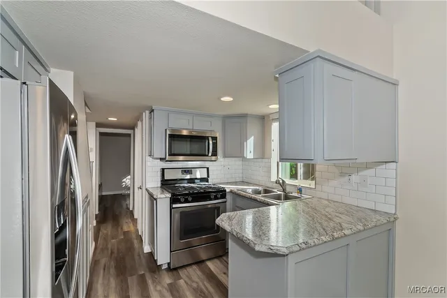 a kitchen with stainless steel appliances granite countertop a sink stove and refrigerator