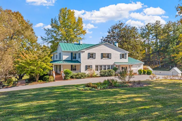 a front view of a house with a yard and a large tree