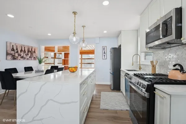 a large kitchen with stainless steel appliances granite countertop a stove a sink dishwasher a microwave oven with cabinets and wooden floor