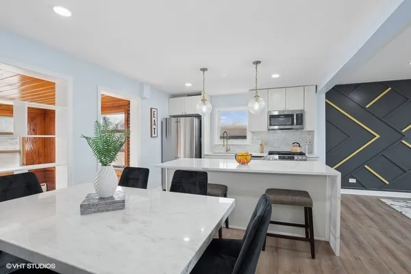 a kitchen with stainless steel appliances a white refrigerator a stove a sink dishwasher with a dining table and chairs