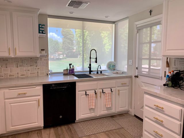a kitchen with white cabinets and a large window