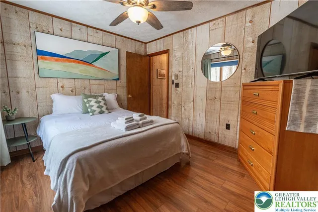 a bedroom with a bed a dresser and painting on the wall