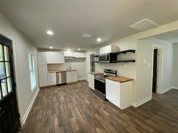 a kitchen with stainless steel appliances granite countertop a refrigerator a stove and a wooden floors