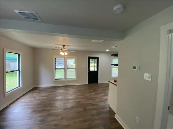 an empty room with wooden floor and windows