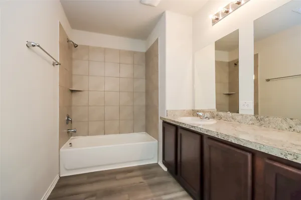 a bathroom with a granite countertop bathtub sink vanity and mirror