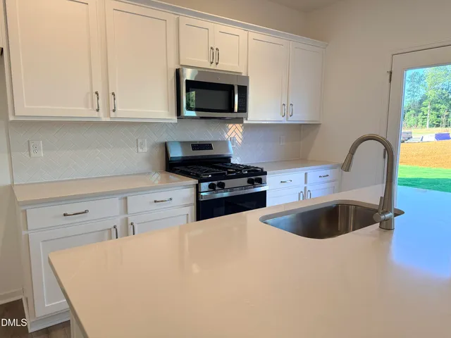 a kitchen with granite countertop a stove a sink and a microwave