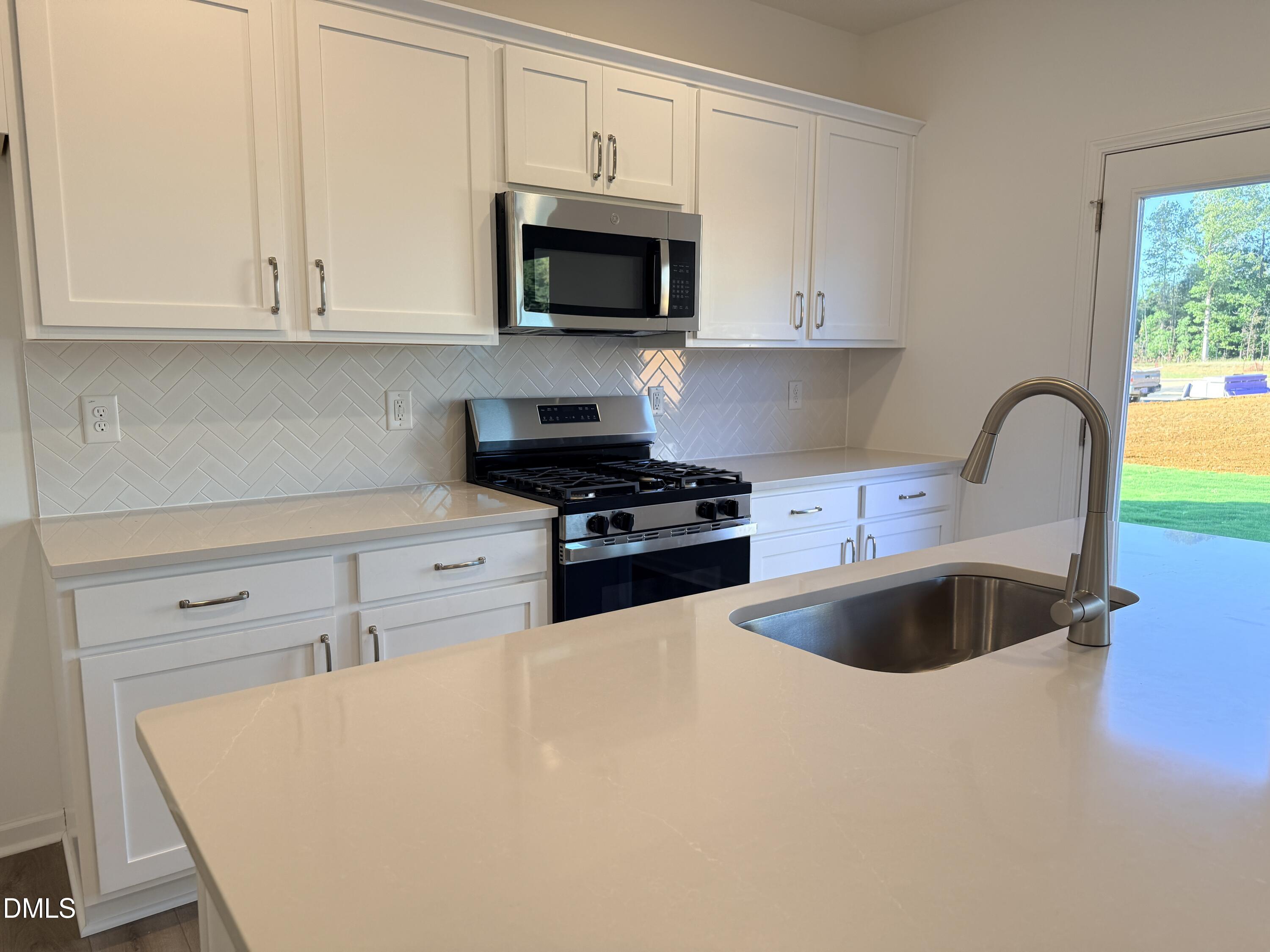 1520 Mirth Court Rolesville, NC 27571 - Photo 1 of 13 a kitchen with granite countertop a stove a sink and a microwave