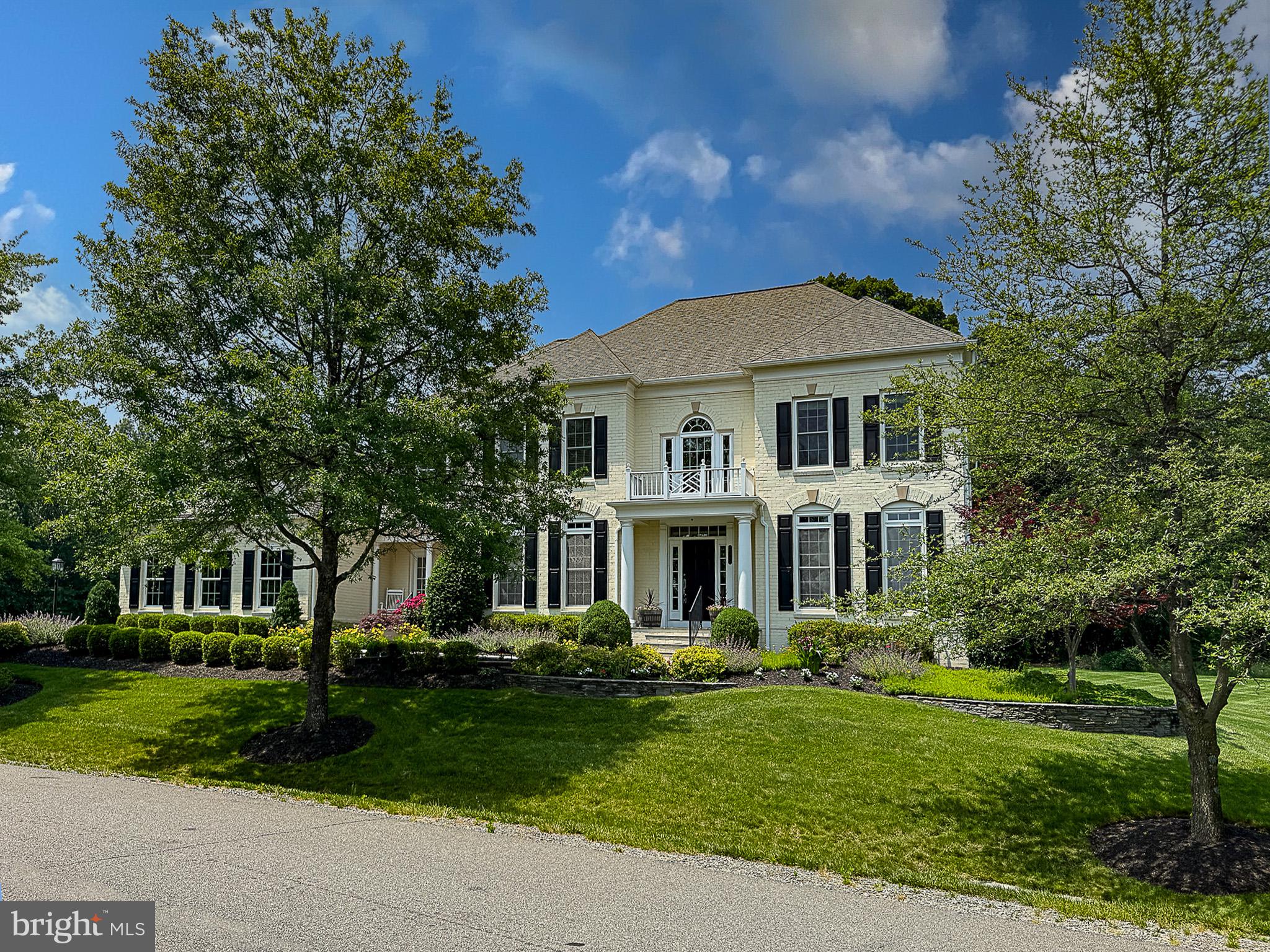 a front view of a house with a garden and trees