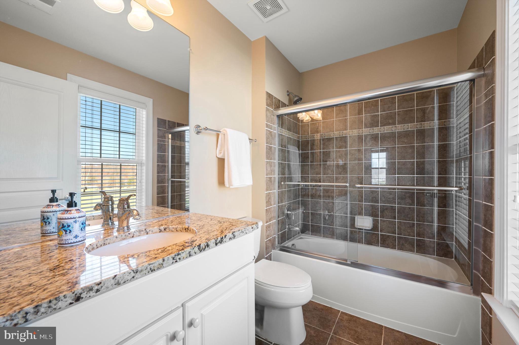 20899 McIntosh Place Leesburg, VA 20175 - Photo 33 of 69 a bathroom with a granite countertop sink a toilet a mirror a bathtub and shower