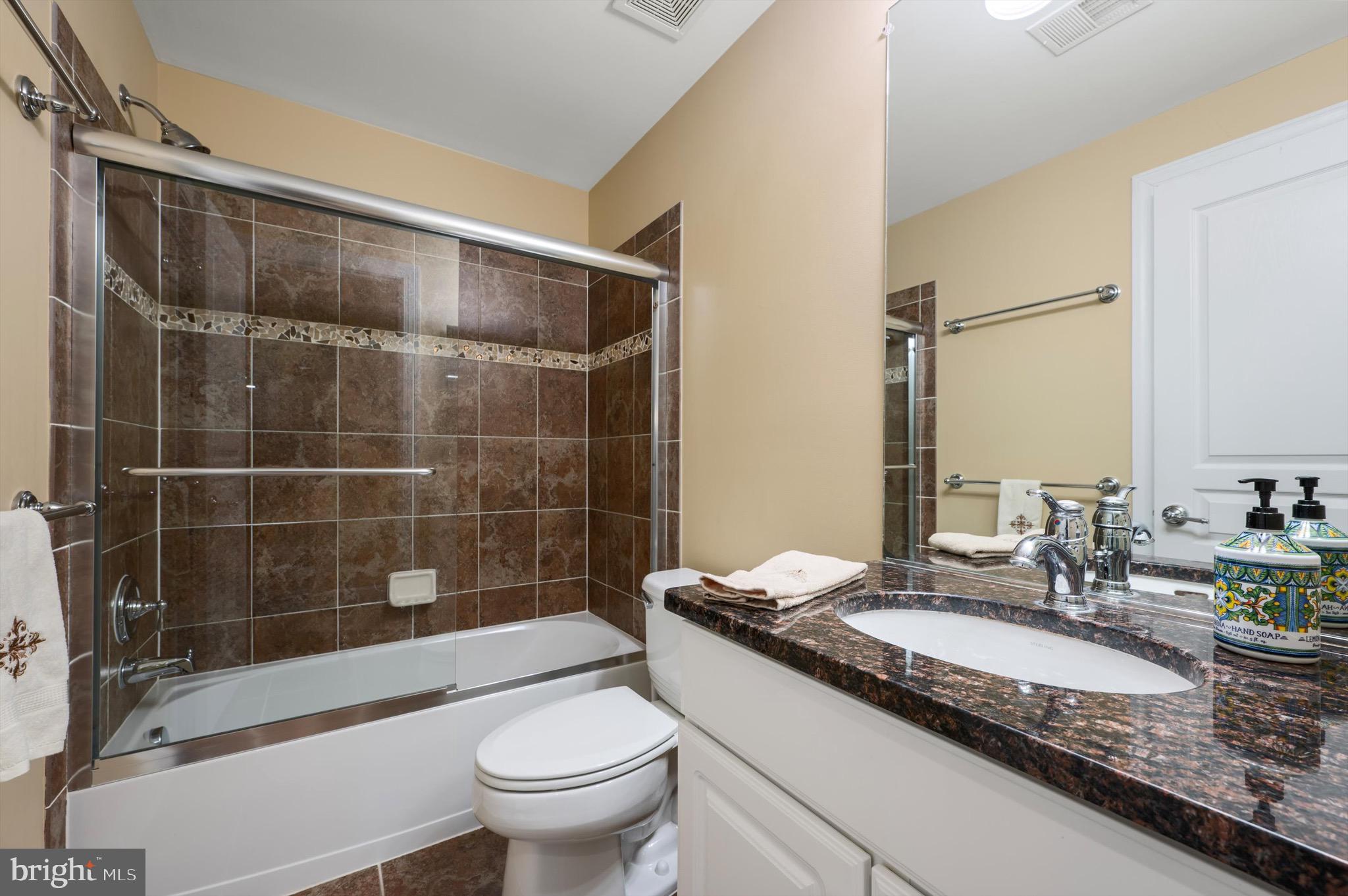 20899 McIntosh Place Leesburg, VA 20175 - Photo 38 of 69 a bathroom with a granite countertop sink a toilet and shower