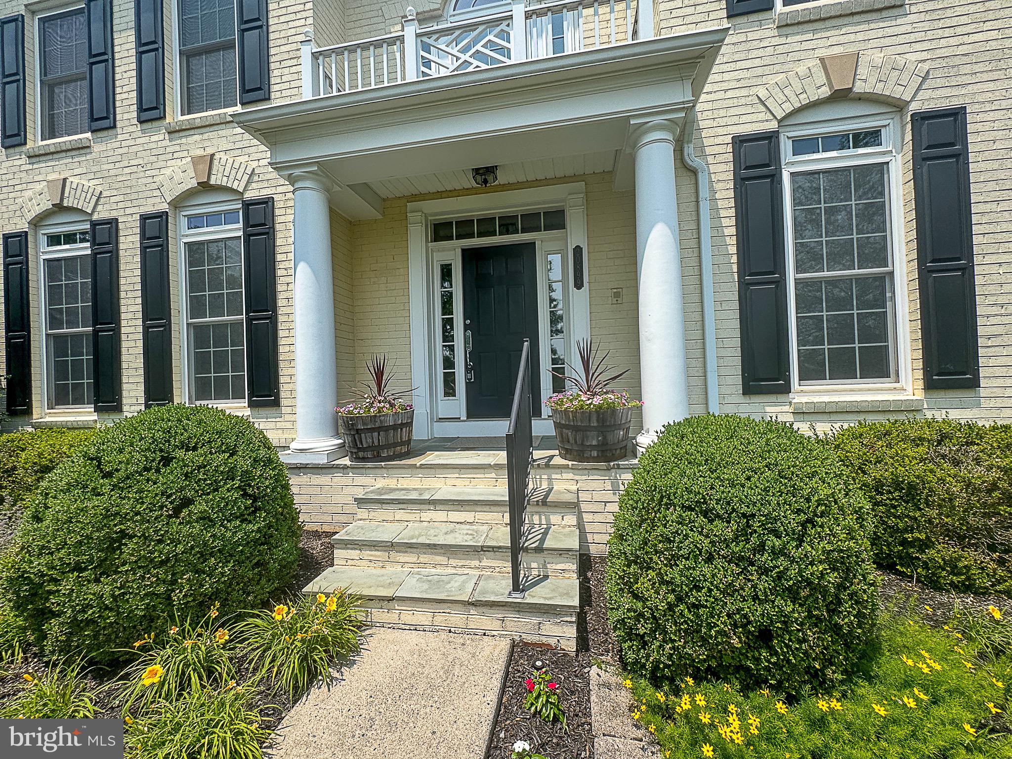 20899 McIntosh Place Leesburg, VA 20175 - Photo 51 of 69 front view of a brick house with a large window and potted plants