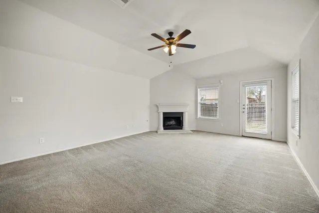 an empty room with windows and fireplace