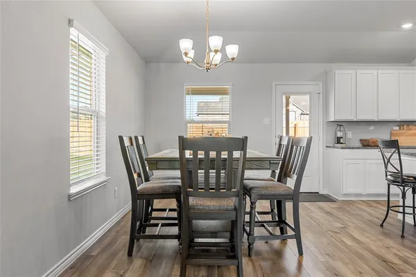 a kitchen with stainless steel appliances kitchen island granite countertop a refrigerator a stove top oven a sink dishwasher and white cabinets with wooden floor