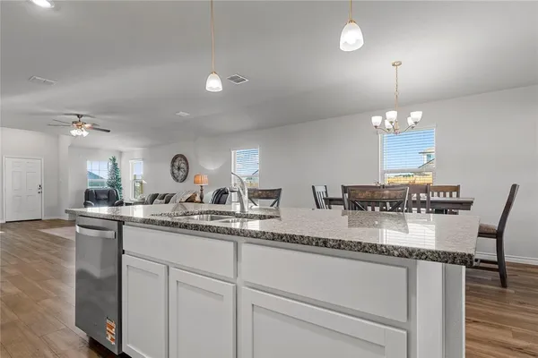 a kitchen with stainless steel appliances granite countertop a refrigerator a sink dishwasher a stove and white countertops with wooden floor