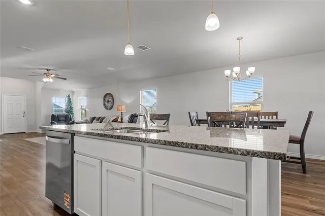 a kitchen with stainless steel appliances granite countertop a refrigerator a sink dishwasher a stove and white countertops with wooden floor