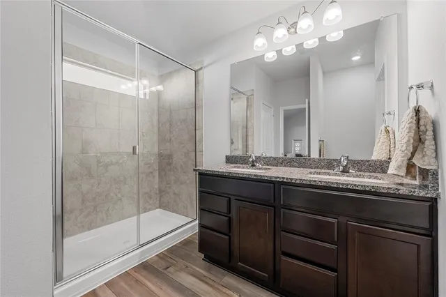 a bathroom with a granite countertop sink a mirror and shower