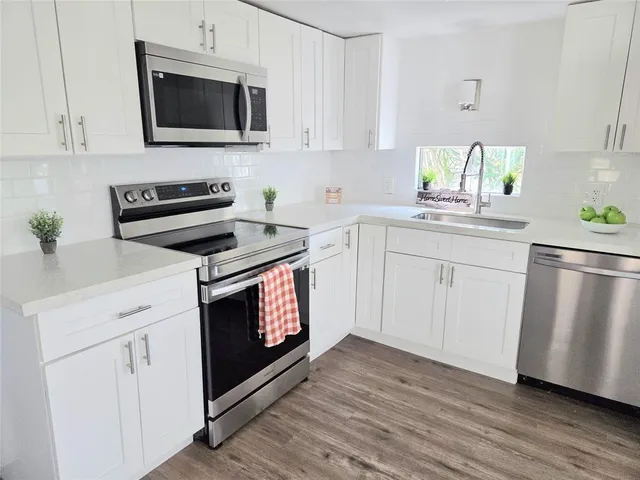 a kitchen with white cabinets stainless steel appliances and wooden floor