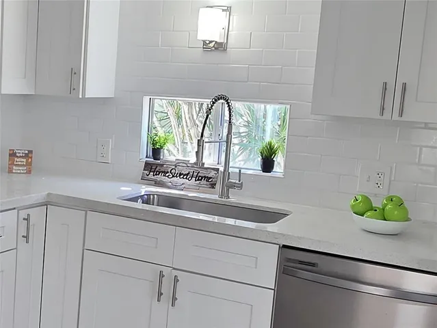 a kitchen with stainless steel appliances white cabinets and a window