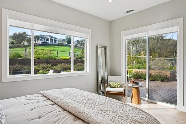 a bedroom with a bed and large windows