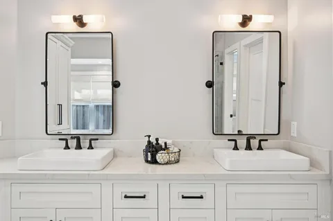 a bathroom with double vanity sink and two mirror
