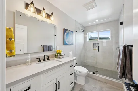 a spacious bathroom with a double vanity sink toilet mirror and shower