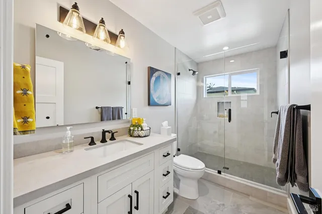 a spacious bathroom with a double vanity sink toilet mirror and shower