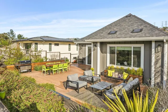 a view of a patio with couches table and chairs with wooden floor and fence