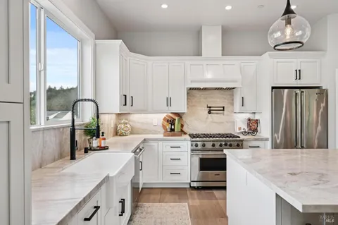 a kitchen with granite countertop a stove a sink and a refrigerator