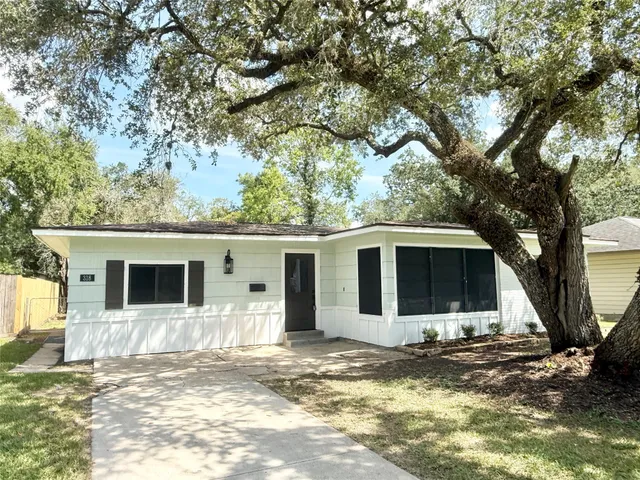 a front view of a house with a tree and wooden fence