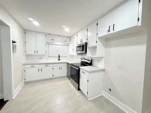 a kitchen with white cabinets stainless steel appliances and sink
