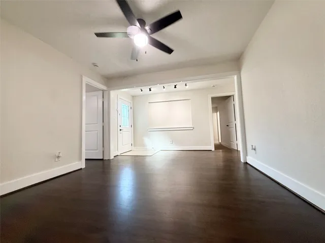 an empty room with wooden floor ceiling fan and windows