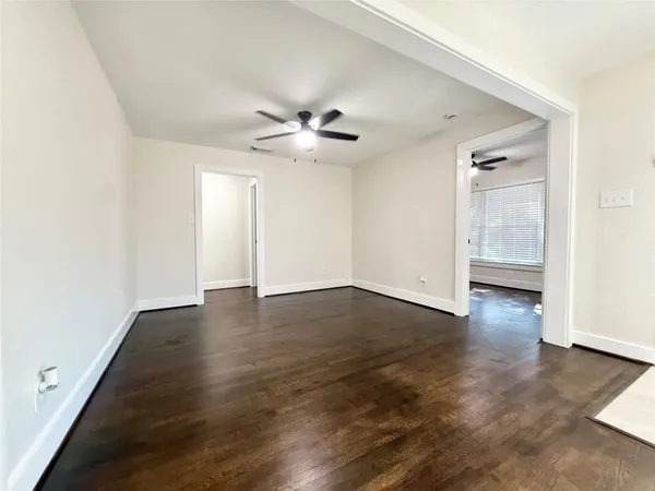 an empty room with wooden floor and ceiling fan