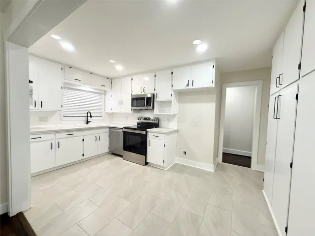 a large white kitchen with a refrigerator a sink dishwasher and a refrigerator with white cabinets